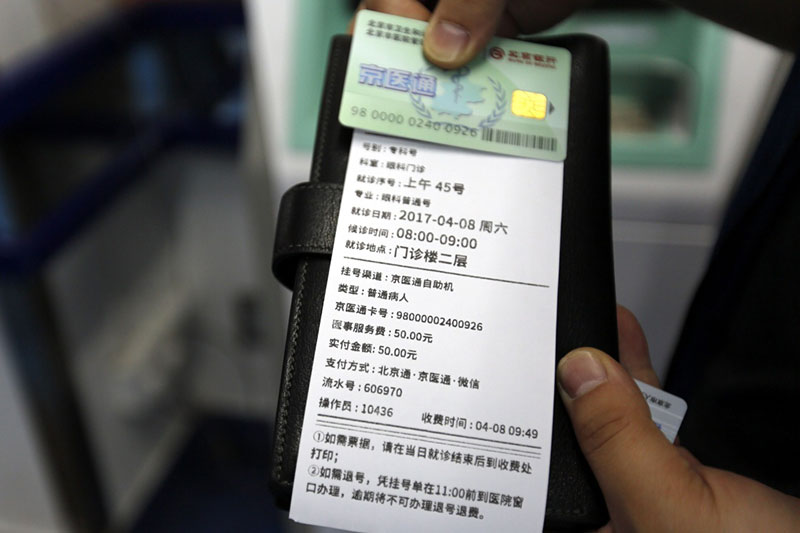 4月8日，一位患者在北京宣武医院展示门诊挂号单，上面的收费项目已改为“医事服务费”。